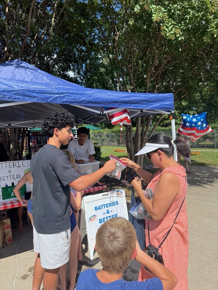 A volunteer helping a resident drop off batteries